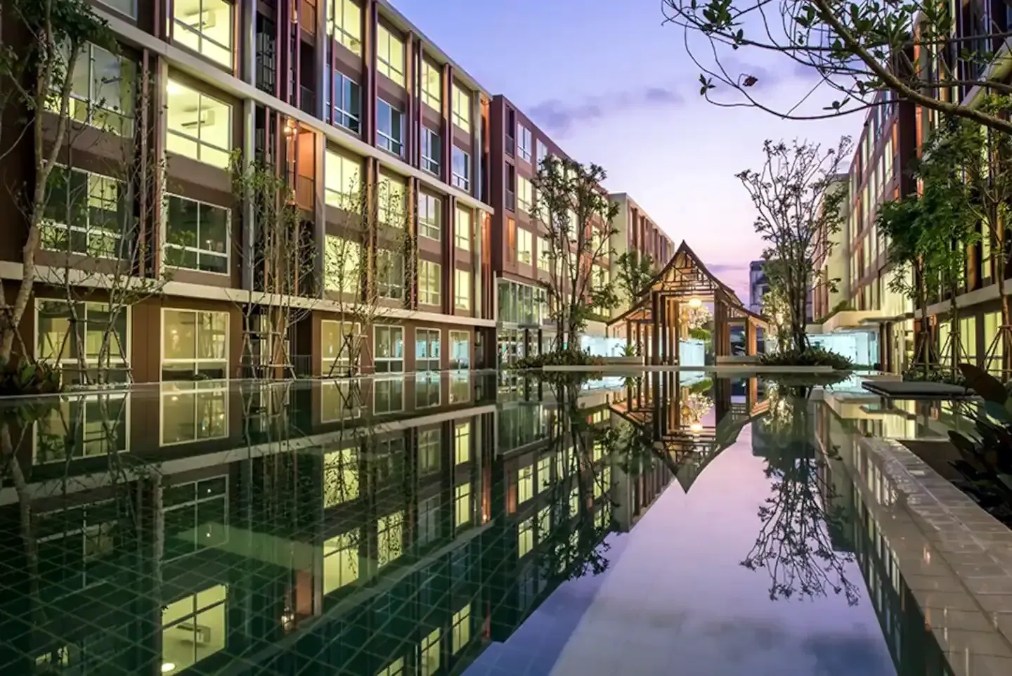 Residence buildings and Lanna pavilion reflected in the garden waterway at dusk